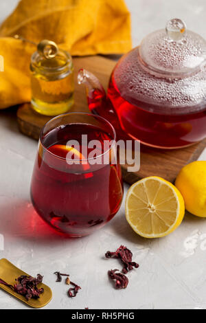 Transparencia copa de té de hibiscus (karkade, agua de flor de Jamaica) con  limón, tetera de cristal, la miel con miel de palo y naranja en la  servilleta blanco volver Fotografía de