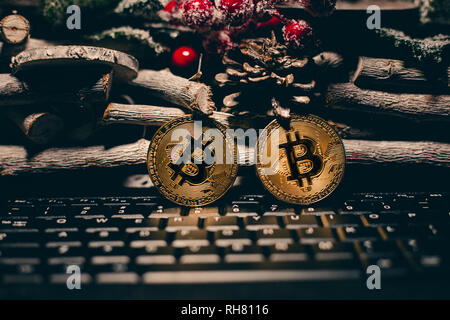 Encendido permanente Bitcoin en el teclado con la navidad de fondo. Dos oro brillante bitcoins en tiempo chrstimas sobre fondo de madera.