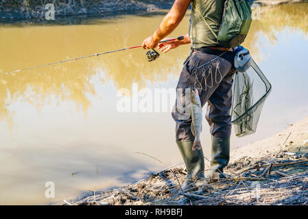 Peces colgando de la correa del pescador con caña de pescar