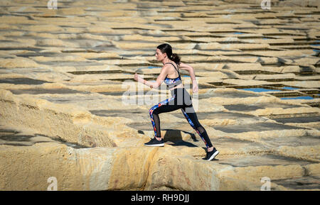 Mujer runner, corriendo a través de la caliza salinas en Malta.