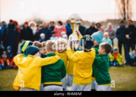 Fondo difuminado de Niños Sport Team con el trofeo. Los niños celebrando el campeonato de fútbol. Feliz jóvenes futbolistas la celebración de la Copa de Oro. Té de fútbol