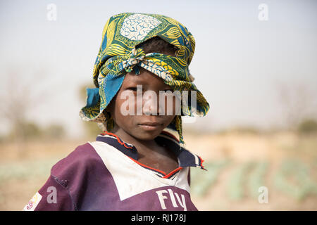La aldea toden, Provincia Yako, Burkina Faso. Un youn g muchacho que ha llegado con su madre a trabajar en su huerta. Foto de stock