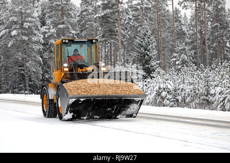 Salo, Finlandia - 25 de enero de 2019: Volvo operador de pala de ruedas transporta una carga ordenada de virutas en el accesorio de cuchara a lo largo de carril de la nieve en invierno. Foto de stock