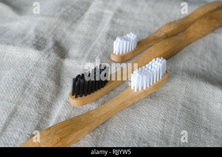Tres cepillos de dientes de bambú en gris de fondo textil Foto de stock