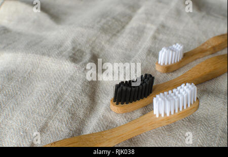 Familiares de tres cepillos de dientes de bambú en gris de fondo textil. Copie el espacio para texto Foto de stock