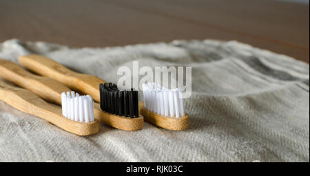 Familiares de tres cepillos de dientes de bambú en gris de fondo textil. Copie el espacio para texto Foto de stock