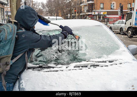 Montreal, Canadá - 7 de febrero de 2019: el hombre limpiando parabrisas de hielo con raspador útil. Foto de stock