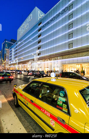 Ginza de Tokio, la hora azul. Taxi amarillo en primer plano con la masiva iluminado Matsuya department store en el otro lado de la calle. Por la noche.