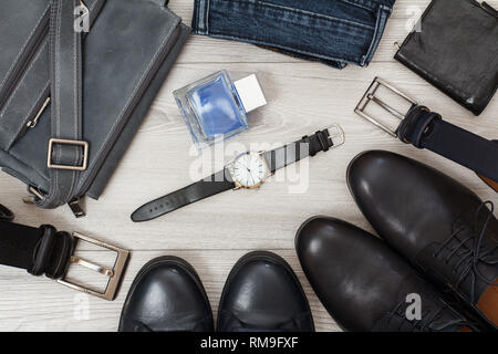 Bolsa para llevar al hombro, dos pares de zapatos de hombre de cuero negro,  correas para hombres, jeans, hombre de colonia, reloj de pulsera y bolso  gris sobre tablas de madera. Los hombres accessori Fotografía de stock -  Alamy