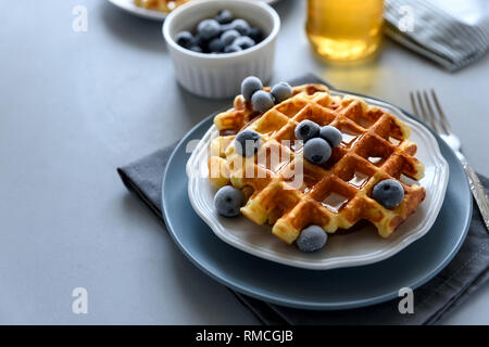 Waffles belgas con arándanos y miel sobre fondo de madera gris. Saludable desayuno casero. Enfoque selectivo Foto de stock