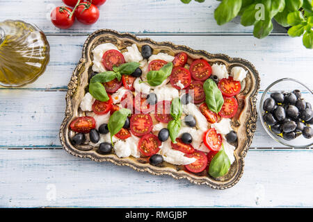 Ensalada Caprese con mozzarella tomates maduros aceitunas y hojas de albahaca. Italiano o mediterráneo, comida saludable. Foto de stock