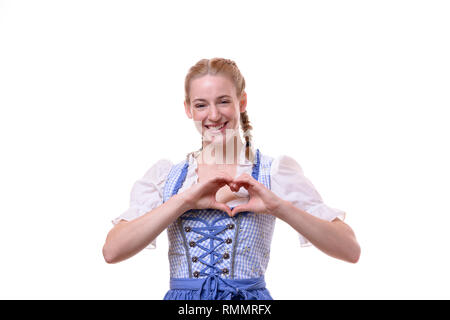 Foto de estudio retrato de una hermosa joven alemán vistiendo traje tradicional bávaro para Oktoberfest mientras sonríe y hace una con forma de corazón Foto de stock