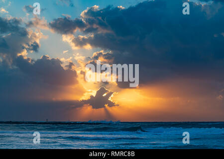 Un atardecer en un cielo nublado sobre el mar mediterráneo, fotografiado en la playa de Tel Aviv, Israel Foto de stock