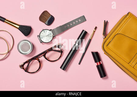 Vista superior del reloj, bolsa, lápiz labial, gafas, sombreador de ojos, brazaletes, mascara y cepillos cosméticos sobre fondo blanco. Foto de stock