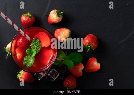 El jugo de fresas y menta fresca en la parte superior y fresa sobre fondo de piedra negra, vista superior y sus bebidas de verano concepto