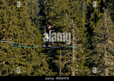 Slackline Walker, en la alta línea entre árboles, ciprés Provincial Park, West Vancouver, British Columbia, Canadá Foto de stock