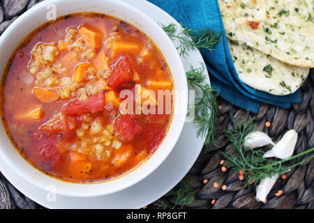 Sopa de Lentejas rojas con patatas y tomates dulces servidos con pan naan, vista superior Foto de stock