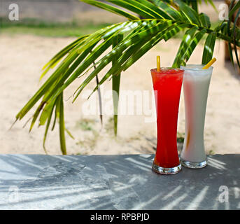 Tequila Sunrise y piña colada cócteles bajo la palma al aire libre Foto de stock