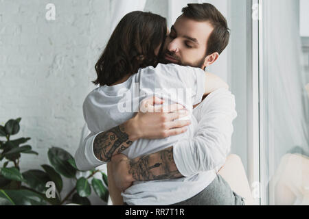 Hermosa joven pareja apasionadamente abrazar en casa Foto de stock