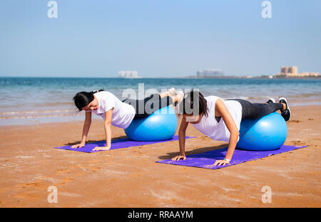 Las mujeres ejerzan con Pilates Pelota de yoga en la playa