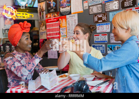 Feliz mujeres jóvenes amigos tostado de cócteles en el bar Foto de stock