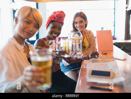 Retrato sonriente, seguros de jóvenes amigas tostado de cócteles en el bar Foto de stock