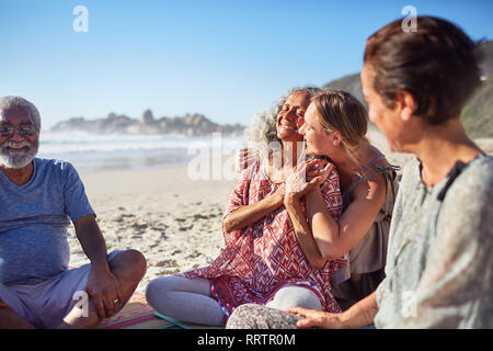 Las mujeres feliz abrazando en sunny beach durante yoga retreat