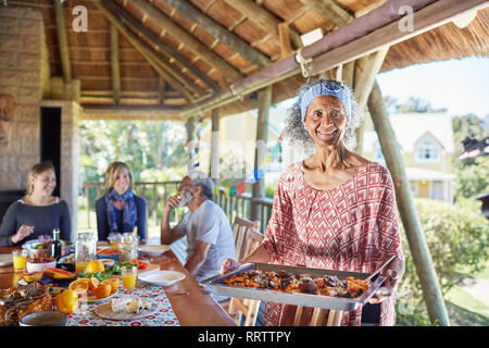 Retrato sonriente mujer senior sirviendo comida a sus invitados en la cabaña Foto de stock