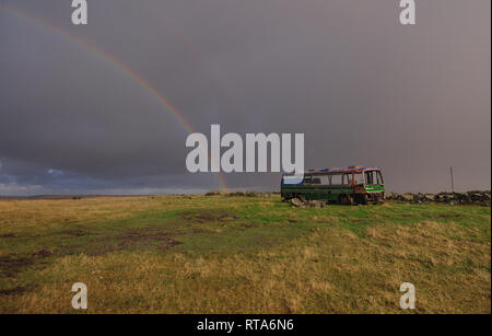 Impresionante paisaje con arco iris y viejo autobús de la isla de Lewis, Escocia