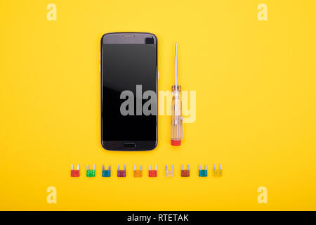 Conjunto de herramientas eléctricas con smartphone negro sobre fondo de colores Foto de stock