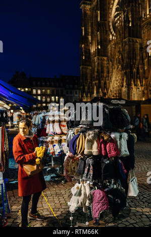 Estrasburgo, Francia - 21 Nov, 2017: mujer mujer elegir sombreros y calcetines de lana tejida en la Plaza de la catedral un día antes de Navidad mercado empieza Foto de stock