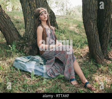 Una chica con ropa hippie sentada sola en el pueblo al aire libre