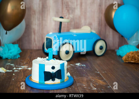 Fotosesión de aplastamiento smashcake para un niño caballero. Fotozona  decorada con un coche retro de madera y globos de helio. Feliz cumpleaños, 1  año: fotografía de stock © Yarkovoy #248652132