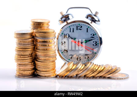 Un montón de monedas de euro en frente de un reloj despertador aislado en blanco.