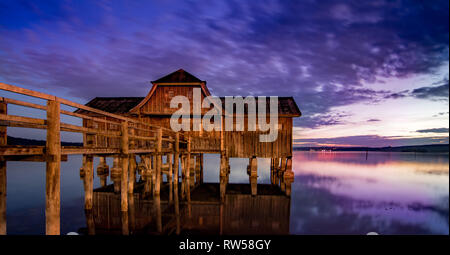 Mystic boathouse de madera en el lago. violoet bávaro amanecer en el lago Ammersee, Alemania Foto de stock