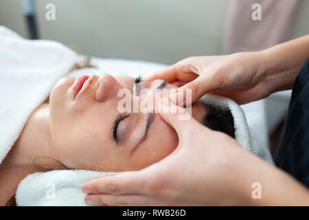 Closeup rostro de mujer joven con un masaje facial en el spa. Foto de stock