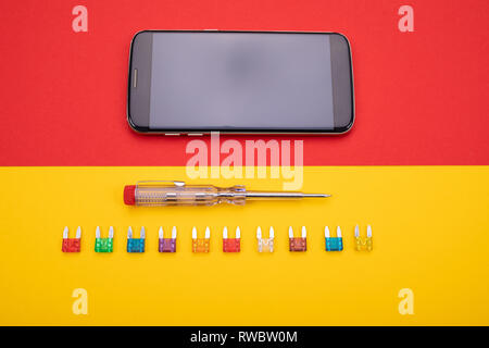 Conjunto de herramientas eléctricas con smartphone negro sobre fondo de colores Foto de stock