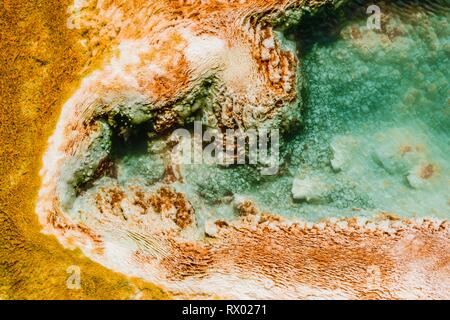 Detalle fotográfico, hot spring con naranja depósitos minerales y paleta de colonias bacterianas, muelles, terrazas superiores
