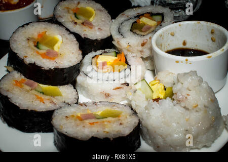 Sushi laminados dispuestos en forma de círculo la placa con una salsa de soja
