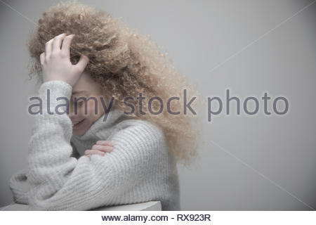 Retrato joven y bella mujer rubia con el pelo rizado y largo la cabeza entre las manos