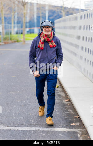 La longitud completa de la moda Hombre senior con las manos en los  bolsillos escuchando música mientras caminaba por la carretera en el parque  Fotografía de stock - Alamy