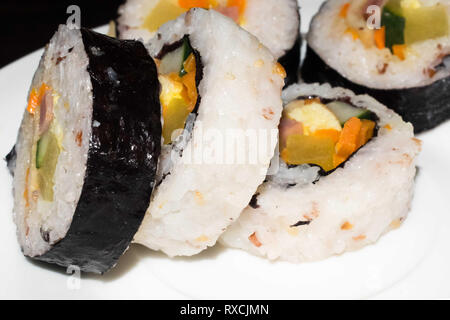 Roll sushi coreano primer plano sobre una placa blanca.