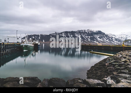 Grundarfjordur, Islandia - 03 de enero de 2019: el puerto con los barcos inmóviles durante el crepúsculo de la tarde, en la montaña volcánica Kirkjufell Foto de stock