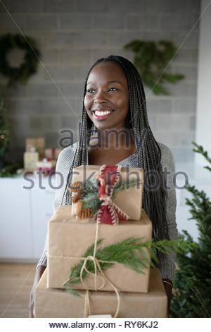 Feliz joven afroamericana sosteniendo la pila de regalos de Navidad