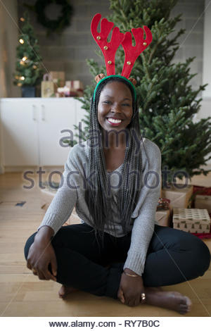 Retrato feliz hermosa joven afroamericana portando cuernos de reno de Navidad