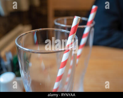 Dos bebidas con gafas de rayas creemos pajitas de papel sobre una mesa de café de madera Foto de stock