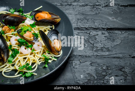 La comida mediterránea. Mariscos espaguetis con almejas. Negro sobre un fondo rústico.
