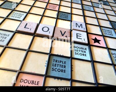 Las palabras 'amor' y 'Me' se exponen en un tablero de Scrabble.