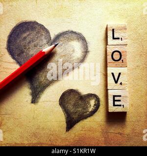 Un simple dibujo a lápiz de dos corazones con un lápiz y la palabra amor escrito con letras de madera Foto de stock