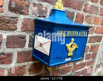 Alemán azul antiguo postbox sobre pared de ladrillo Foto de stock